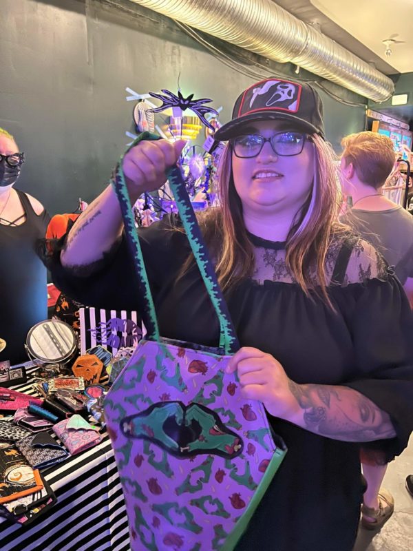 woman holding coffin shaped purse in front of craft table